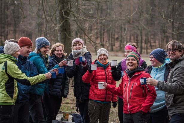 Gruppe von Personen in Winterkleidung stossen mich Gluehweinbechern an.