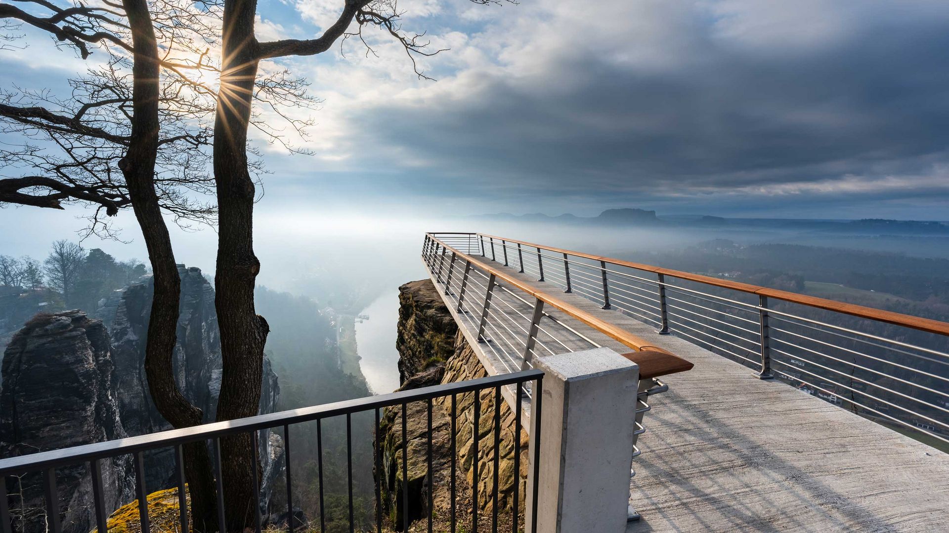 Neue Basteiaussicht: Steinerne Aussichtsplattform über einer Schlucht, bewölkter Himmel im Hintergrund.